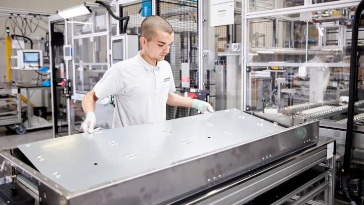 An employee in Germany assembles an Akasol battery pack for a commercial vehicle.